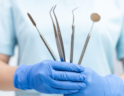 A gloved hand holding dental instruments